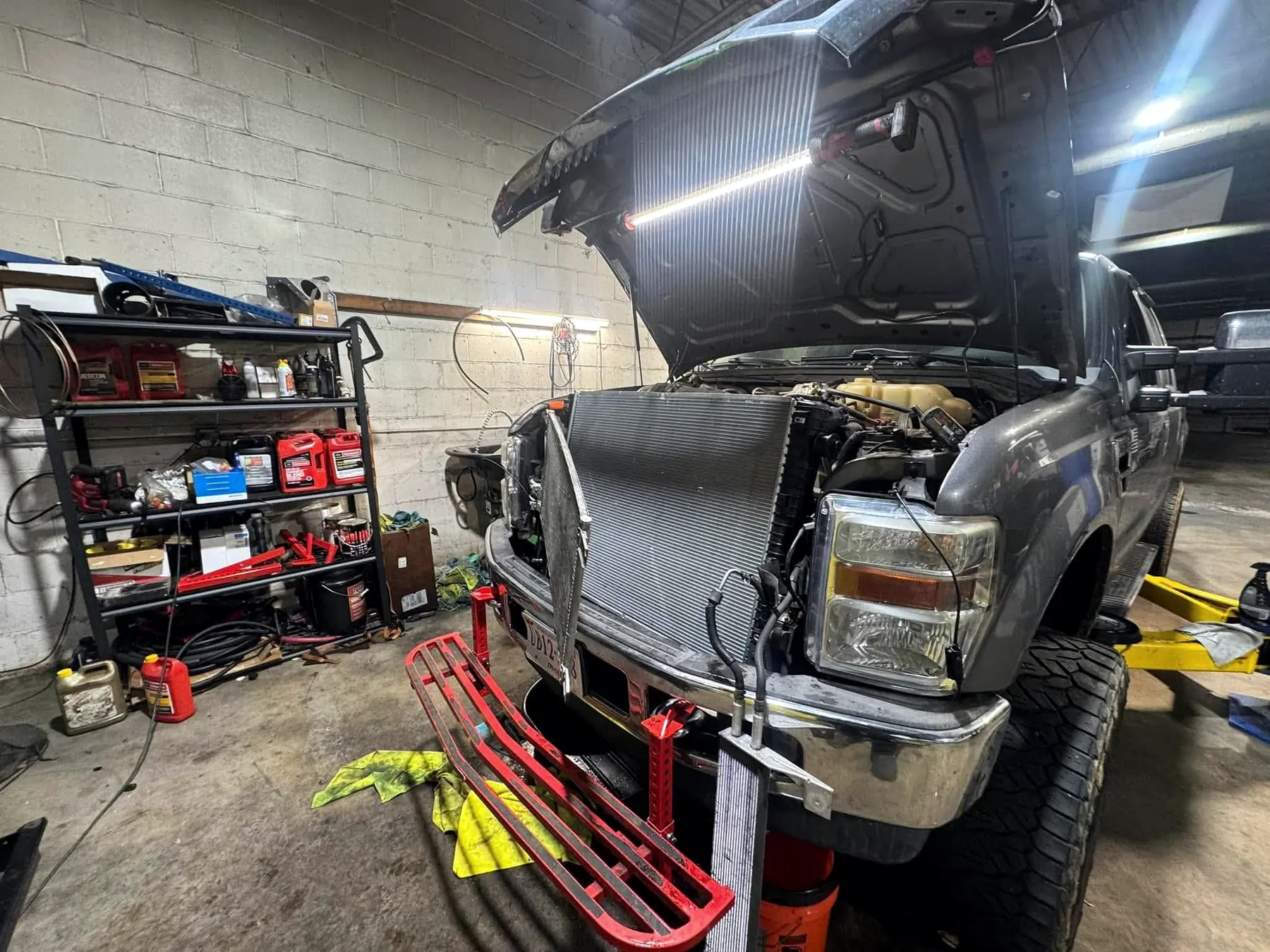 Ford Super Duty with the front end apart and the replacement radiator standing ready on the shop floor