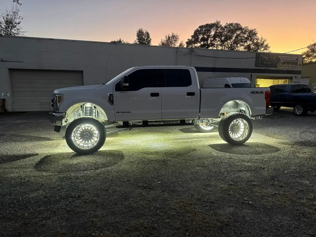 Ford Super Duty on polished wheels lit up at dusk outside the CBS Diesel shop