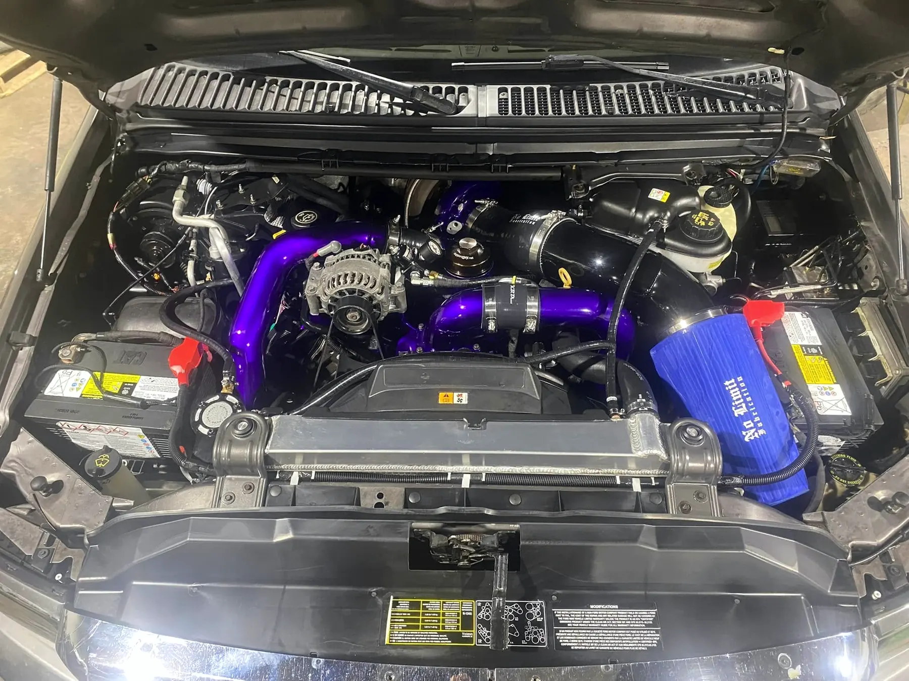 Completed 6.0 Power Stroke engine bay with purple charge pipework and a No Limit Fabrication intake