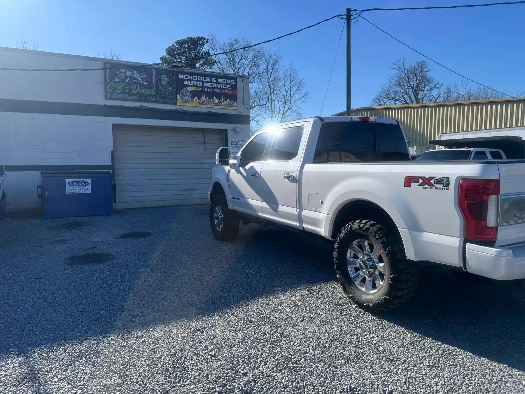 White Ford F-250 FX4 parked in front of the shop's roll-up doors