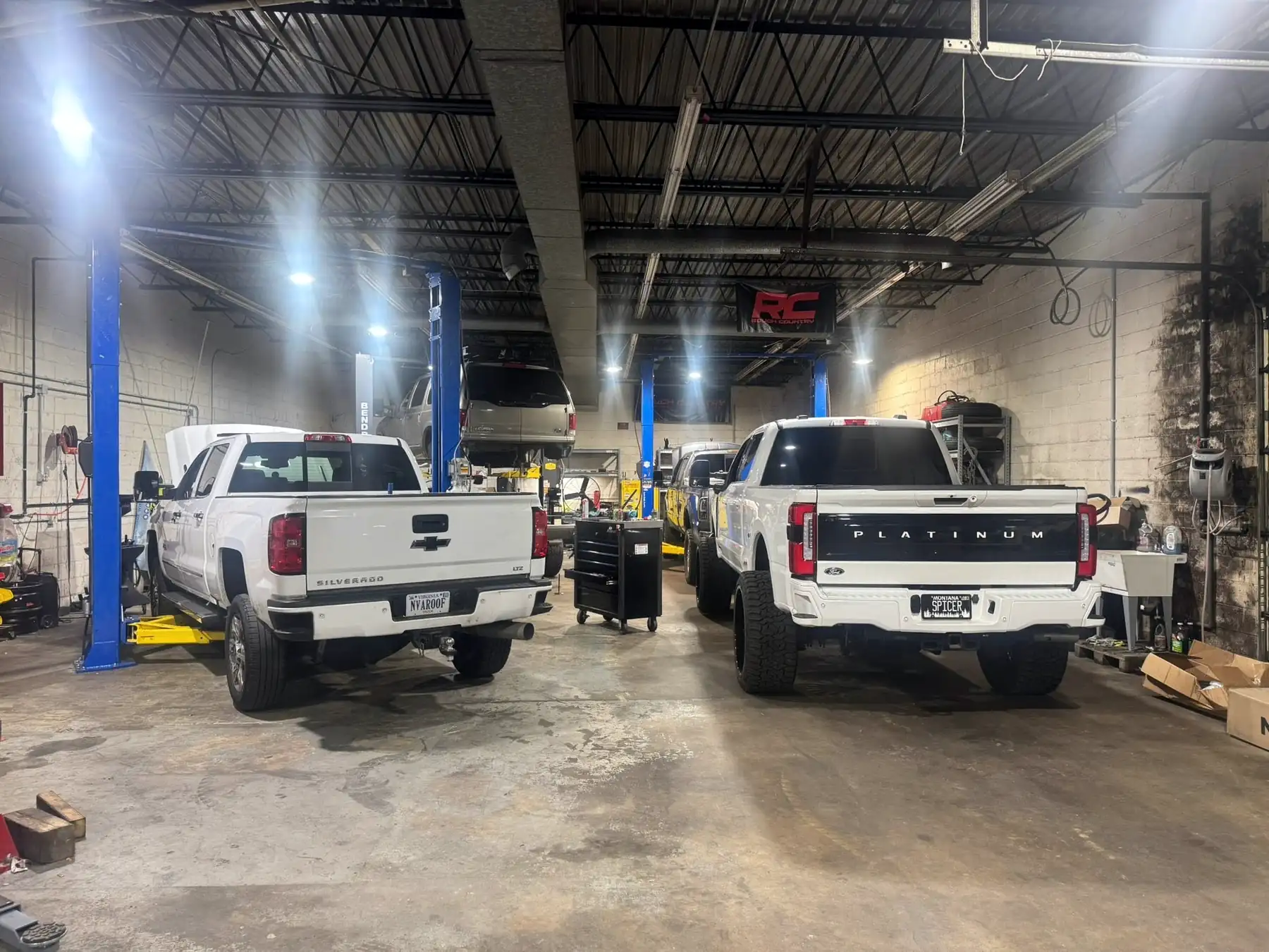 A Silverado and a Ford F-350 Platinum parked between the lifts at CBS Diesel
