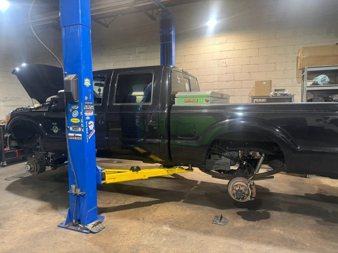 Ford Super Duty with the front suspension stripped on the lift