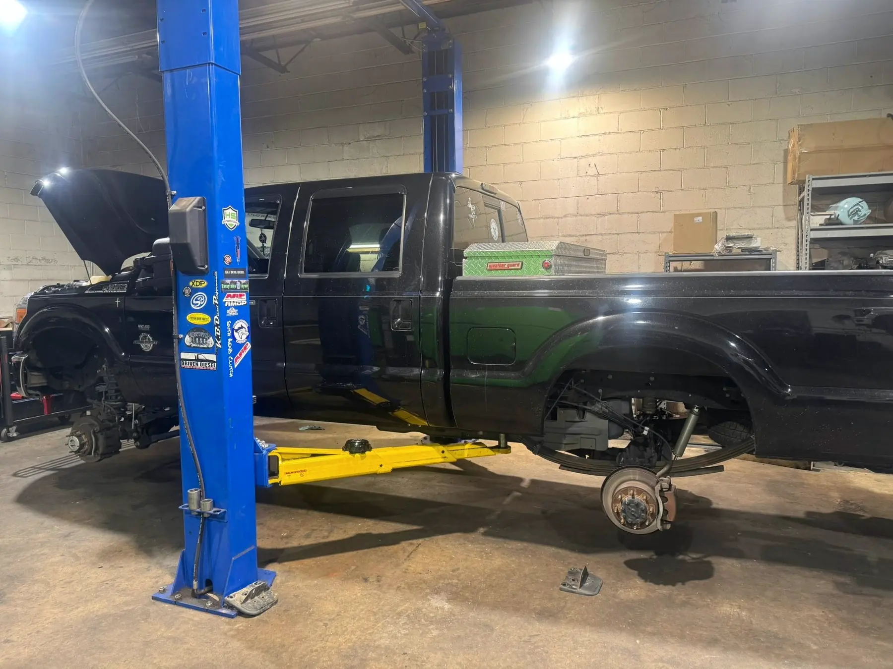 Ford Super Duty with the front suspension stripped on the lift