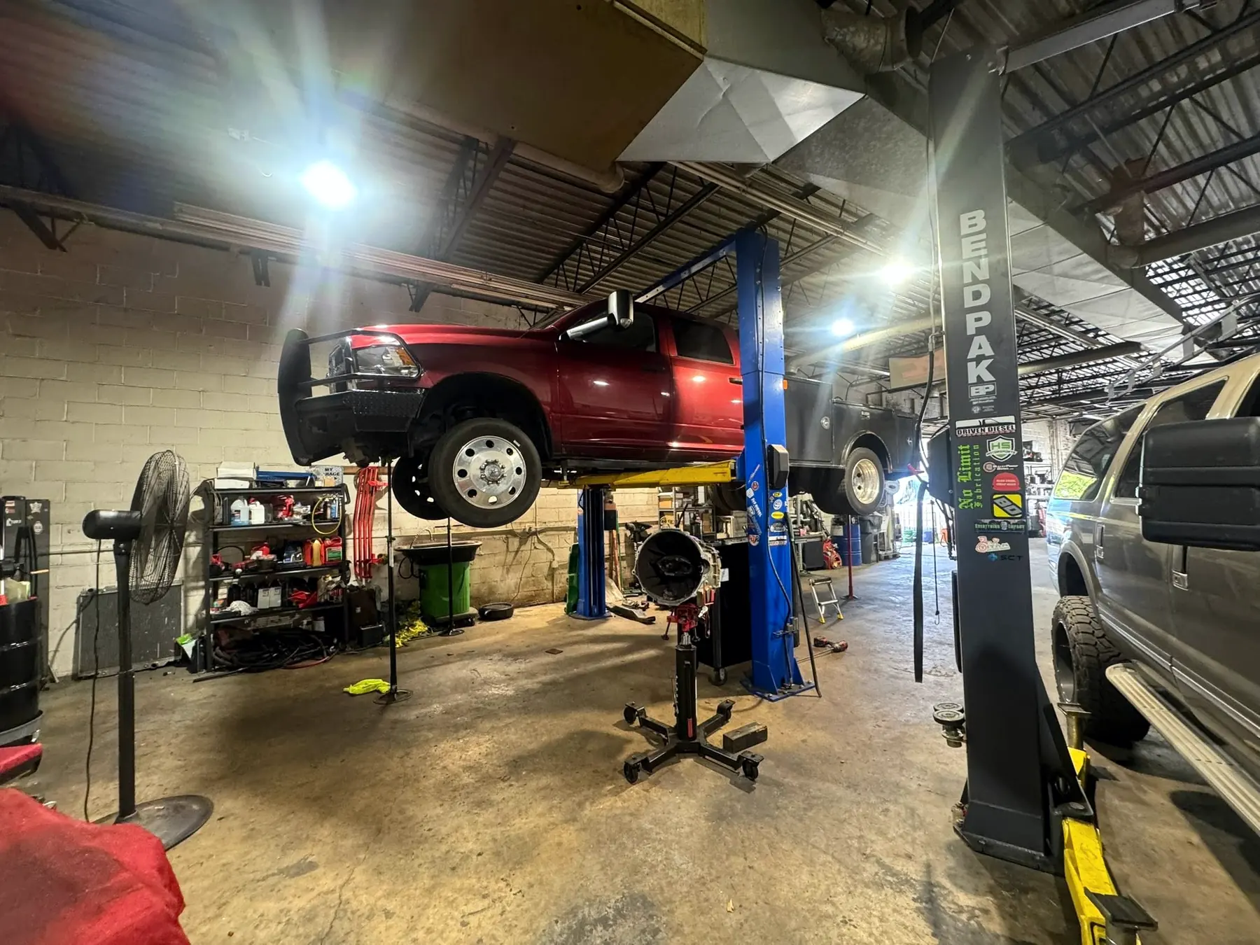 Red Ram on the lift with the transmission being dropped on a jack