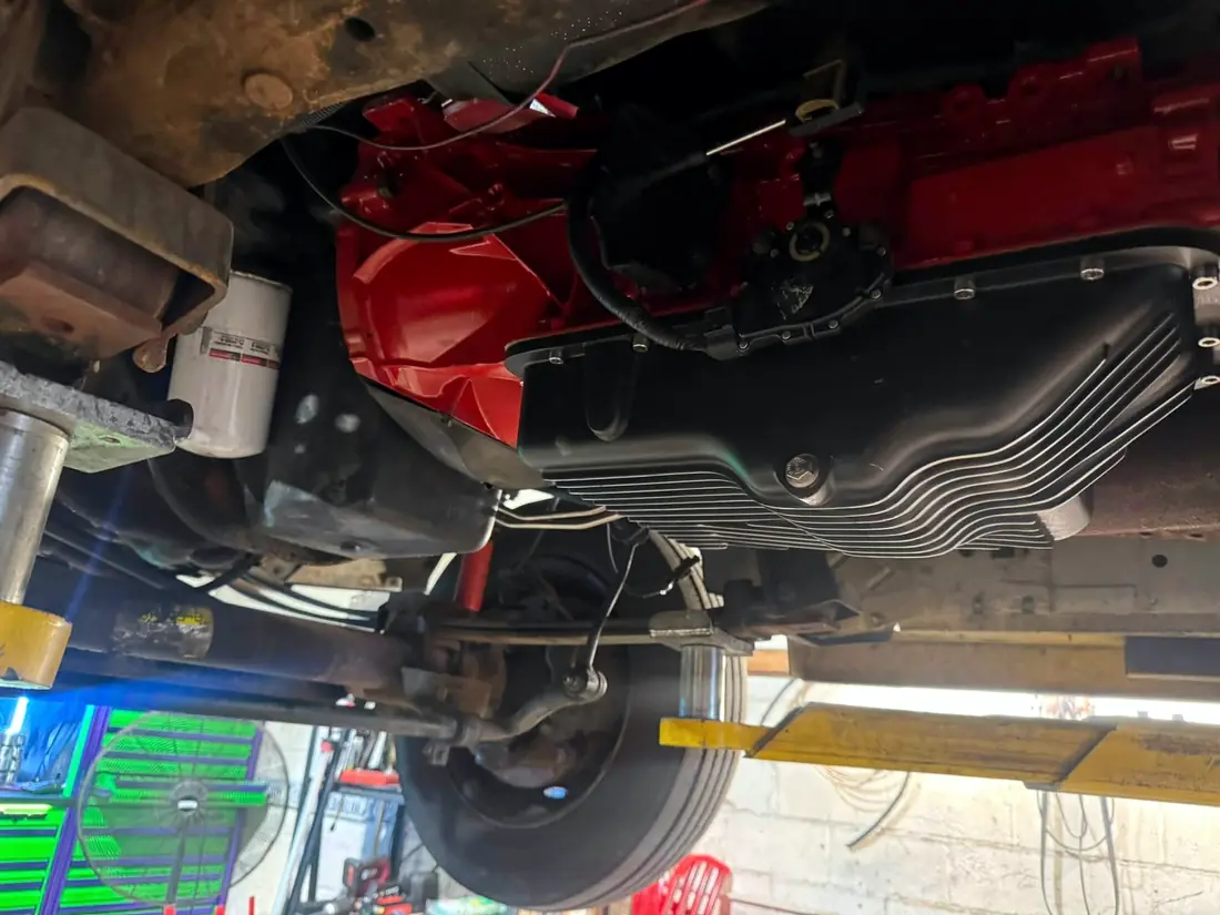 Underside of a red diesel truck showing the transmission pan and exhaust