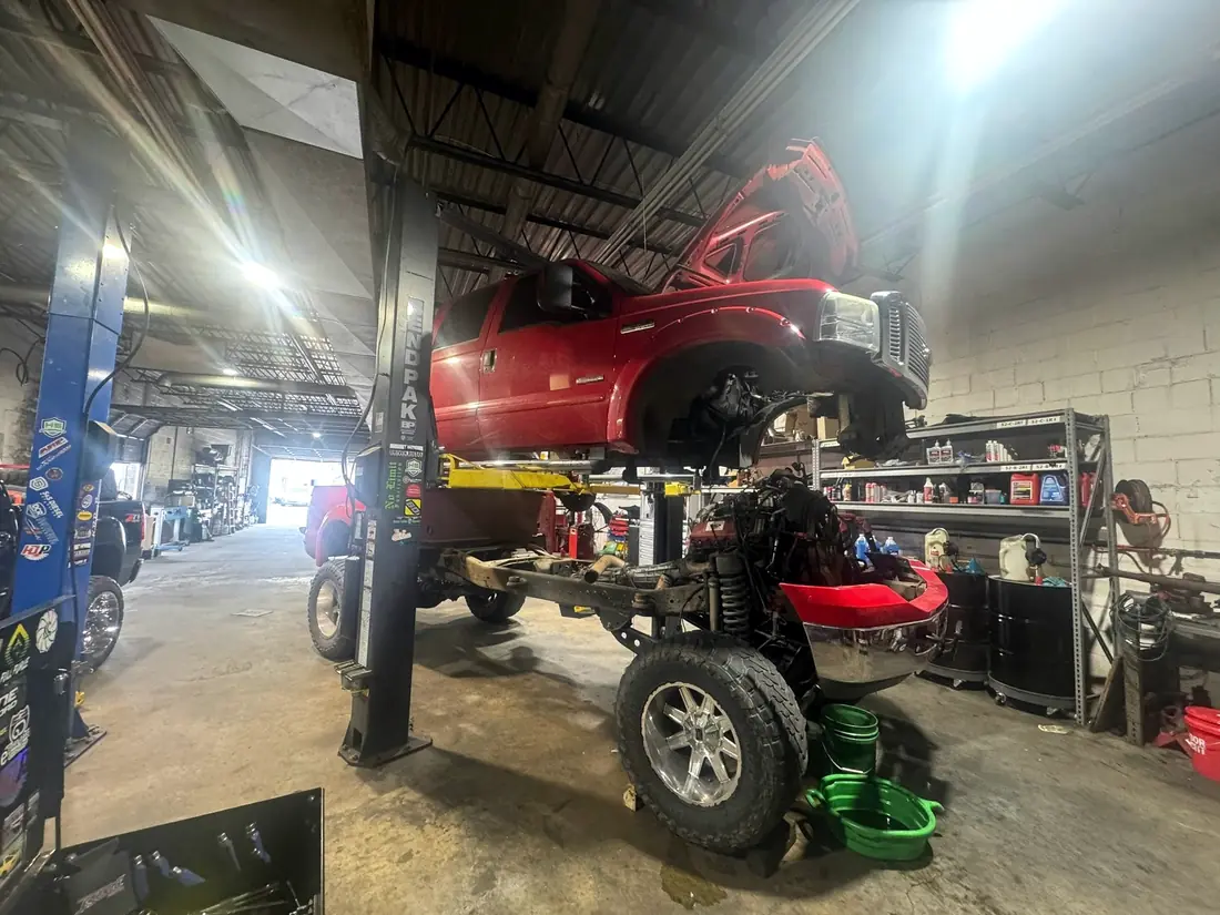 Red lifted truck with the cab removed on the lift