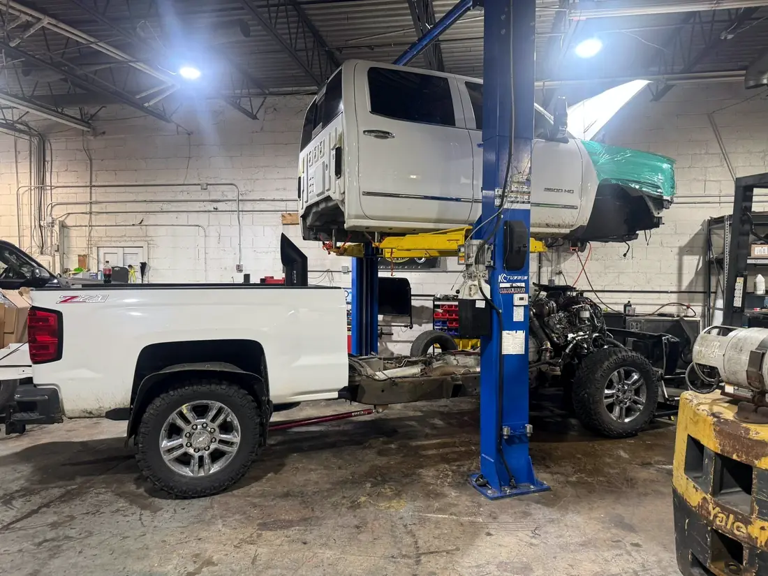 A Silverado and a Ford both raised on lifts at CBS Diesel