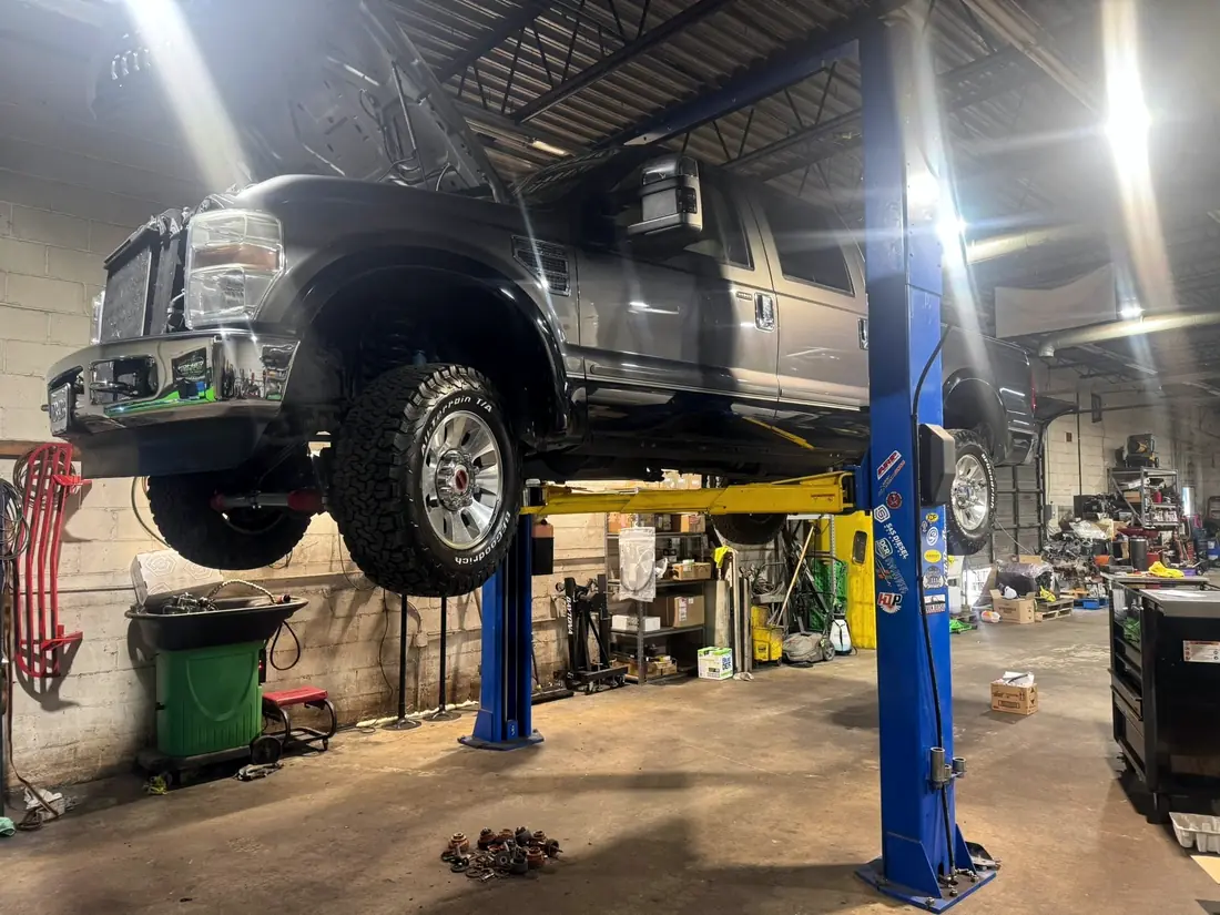 Gray Ford Super Duty high on the two-post lift