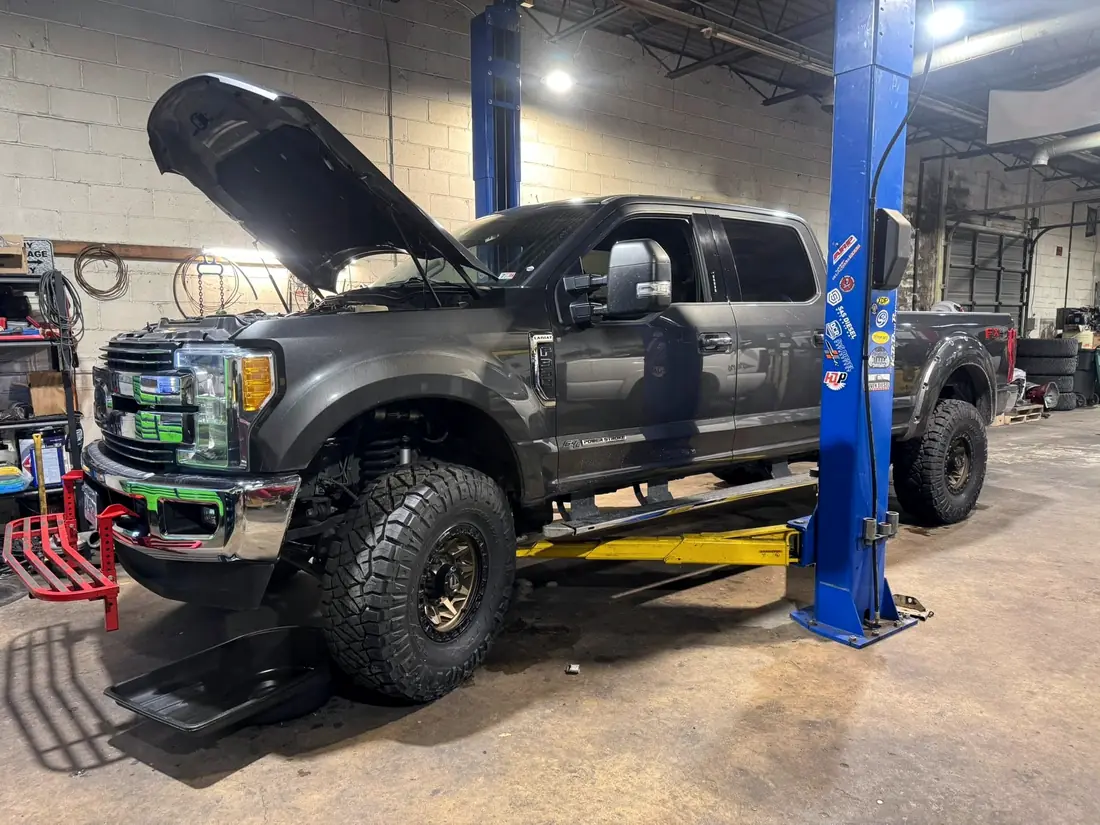 Gray Ford Super Duty on the lift with the hood up