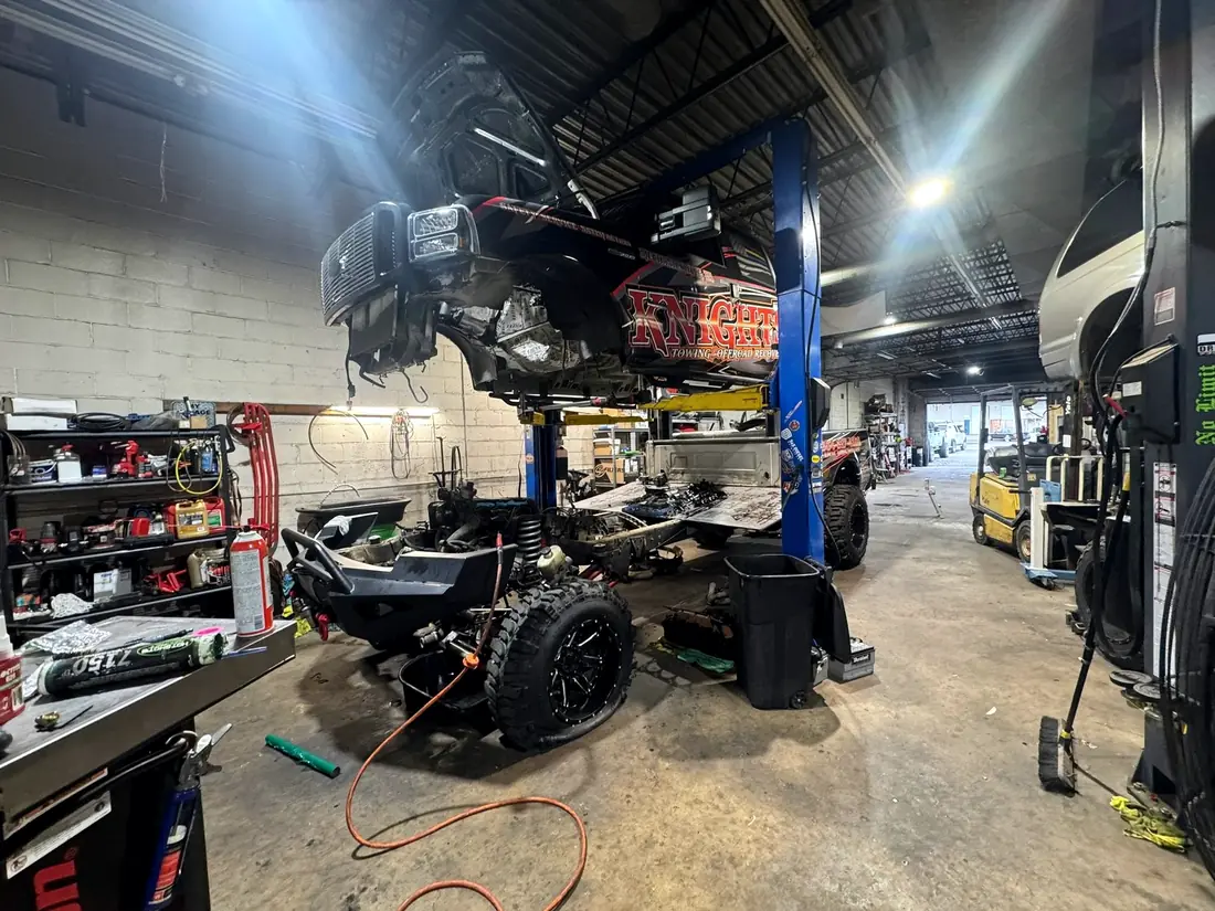 Wide shop view with a truck stripped down on the lift