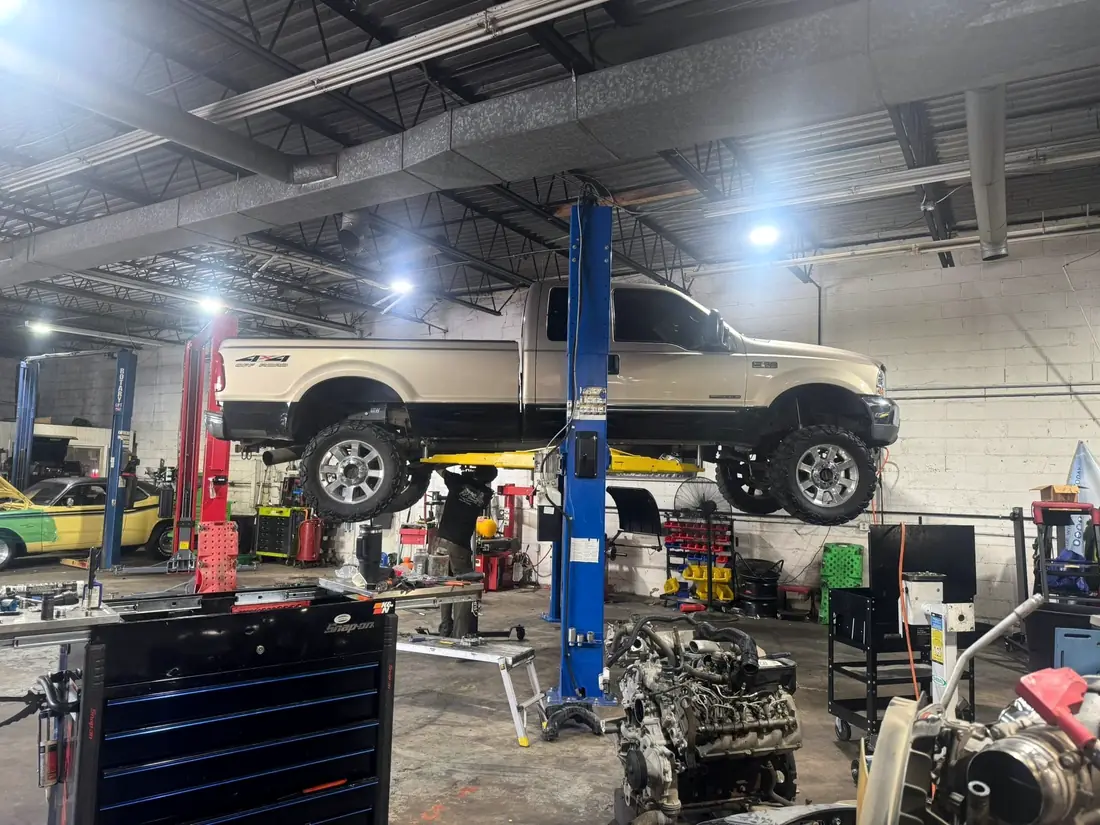 White Ford Super Duty raised high on the lift