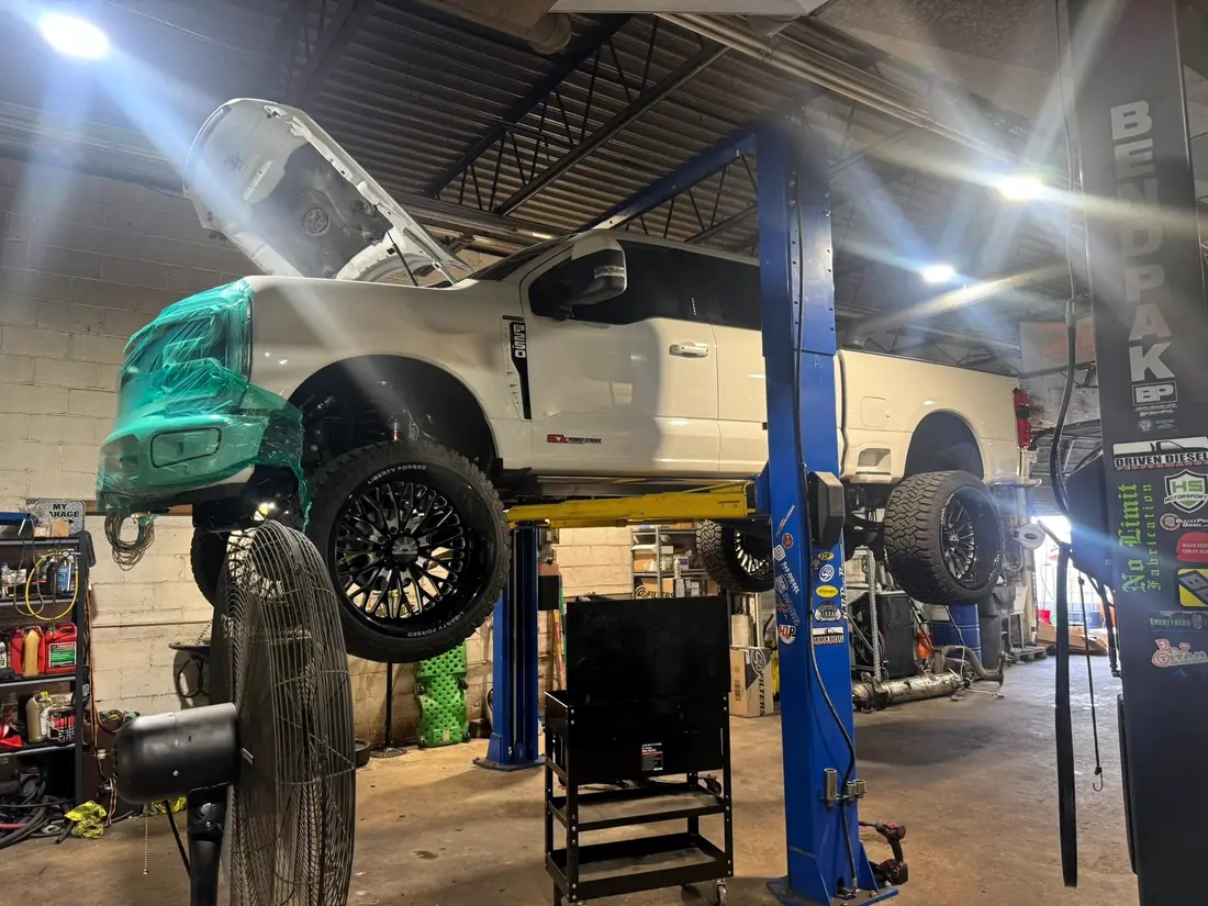 White Ford F-350 with the front clip removed on the lift