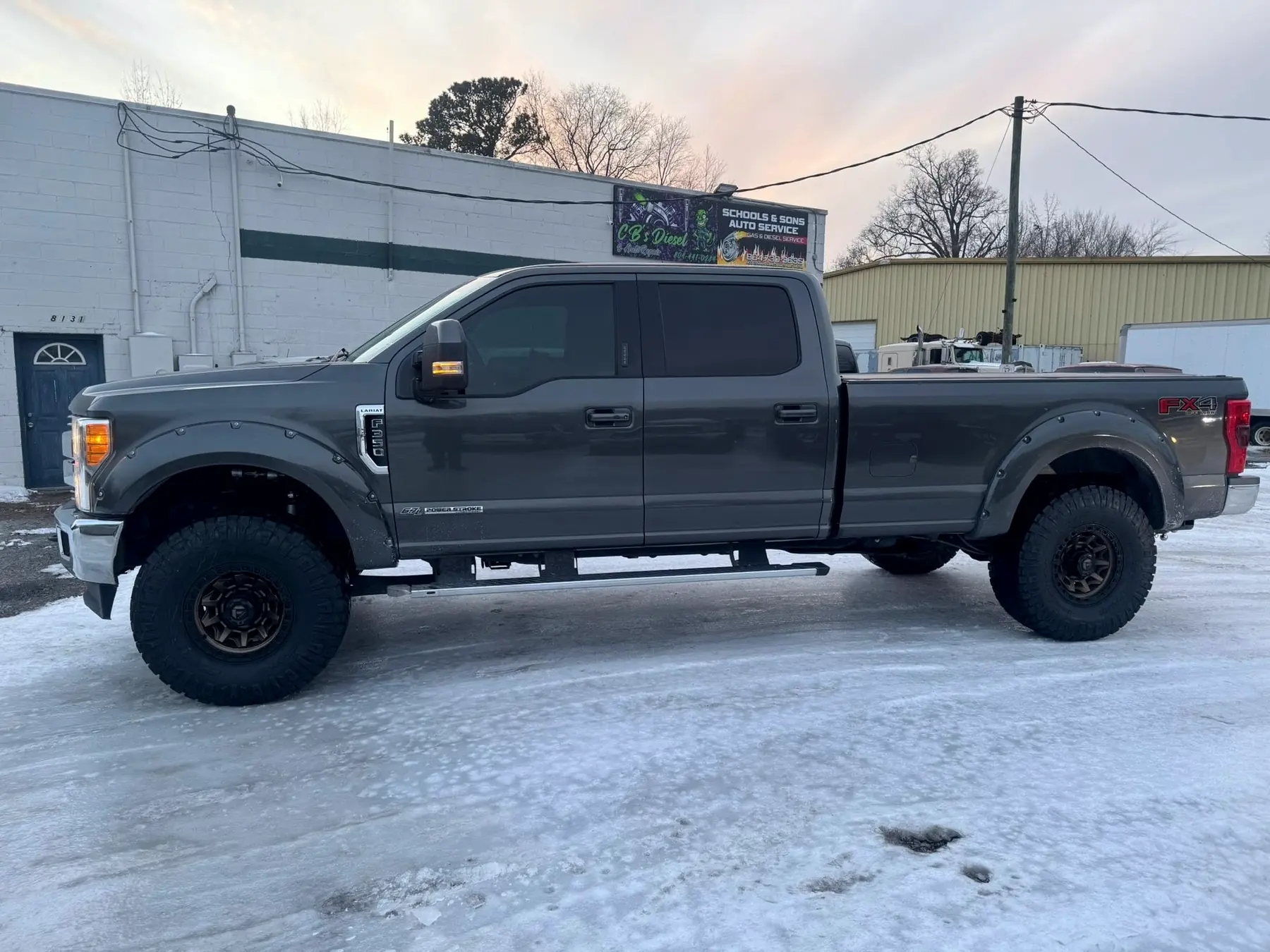 Gray Ford F-250 Tremor on aftermarket wheels in the snow outside the shop